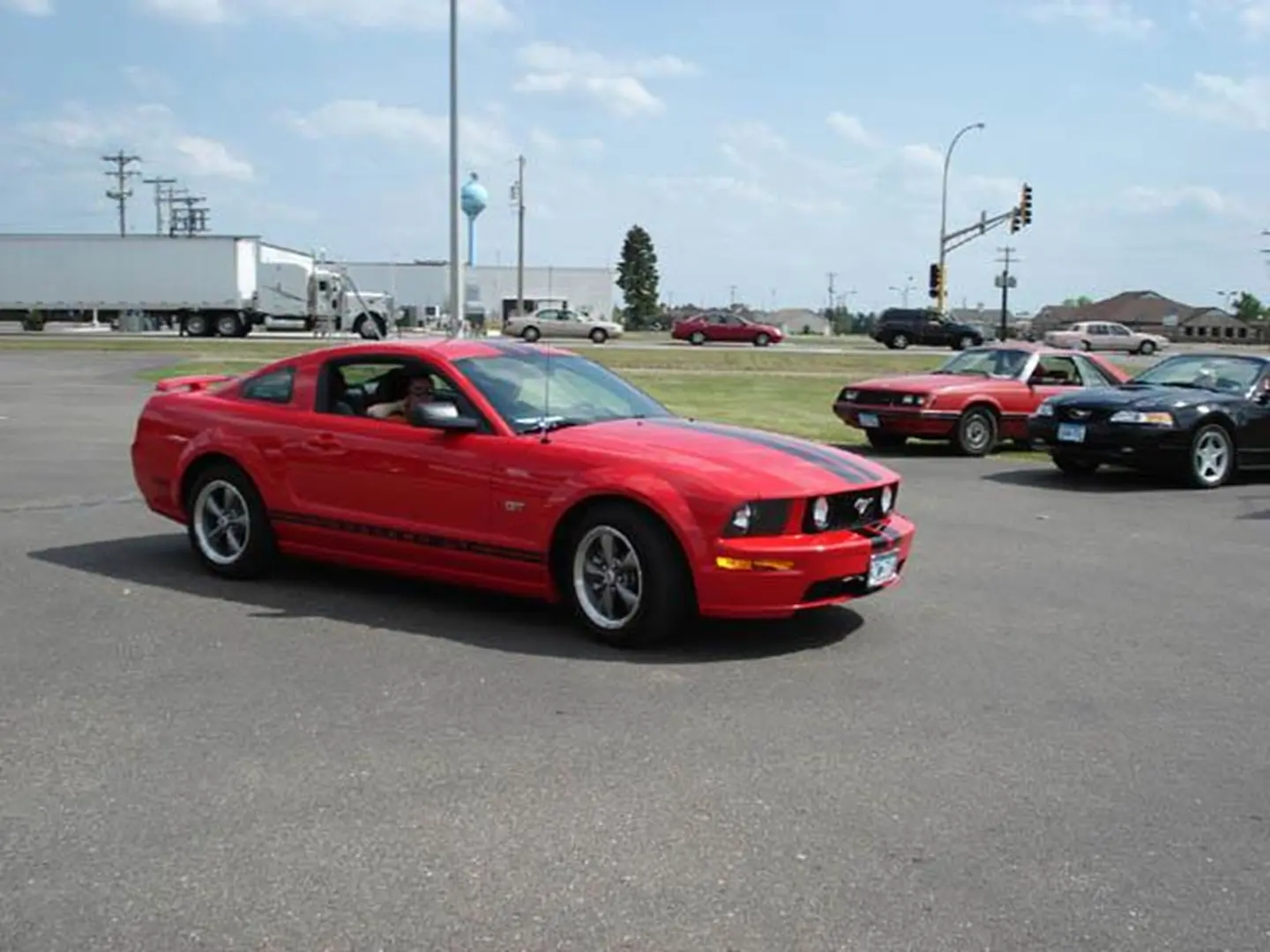 Red Mustang with other cars nearby