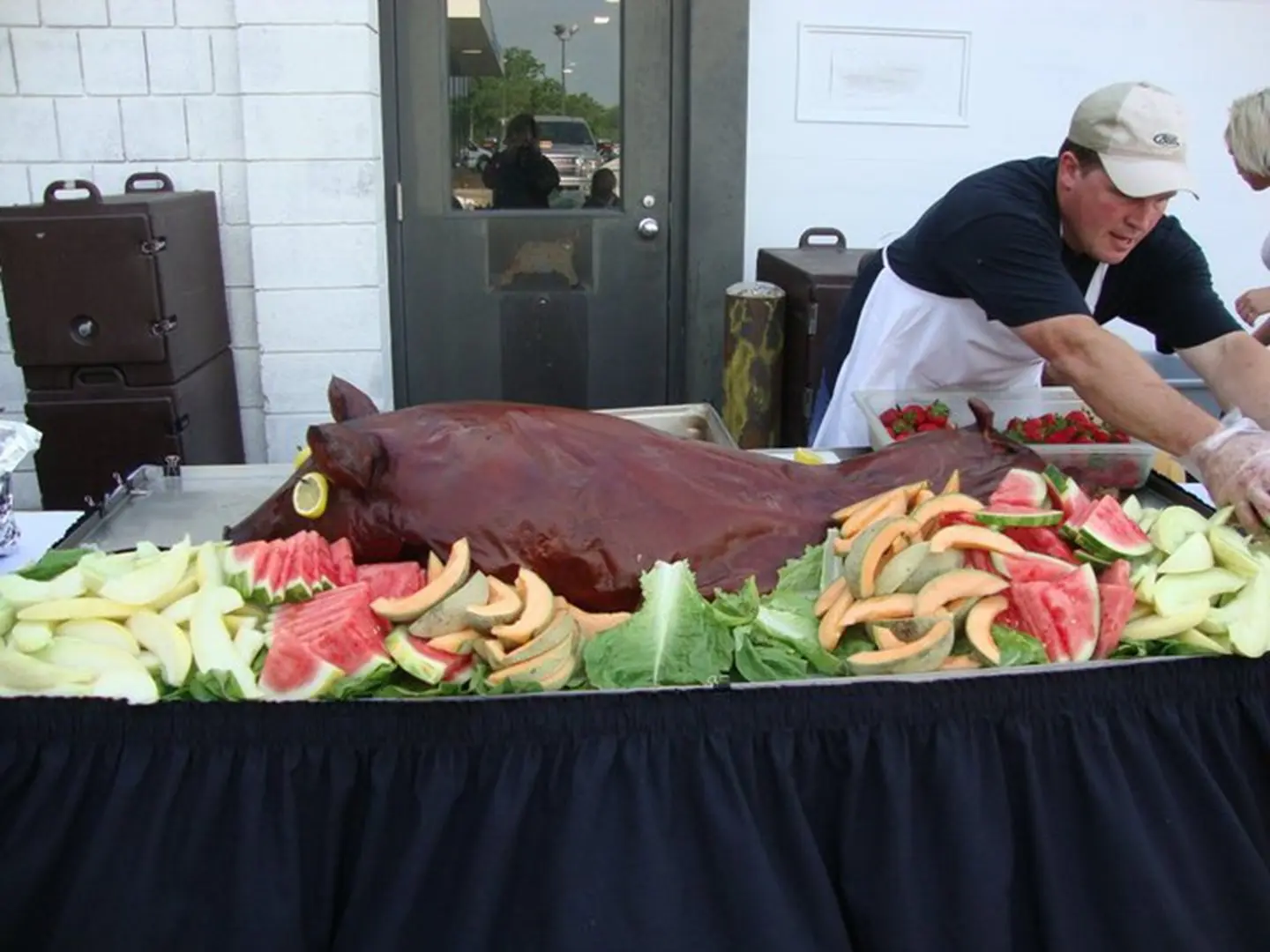 Outdoor buffet with whole pig and fruits