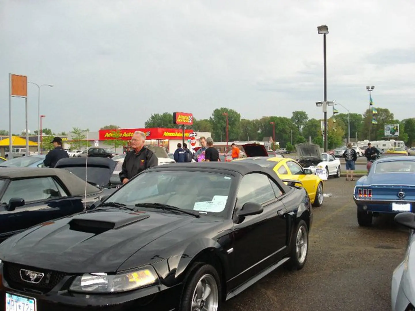 People viewing cars in parking lot