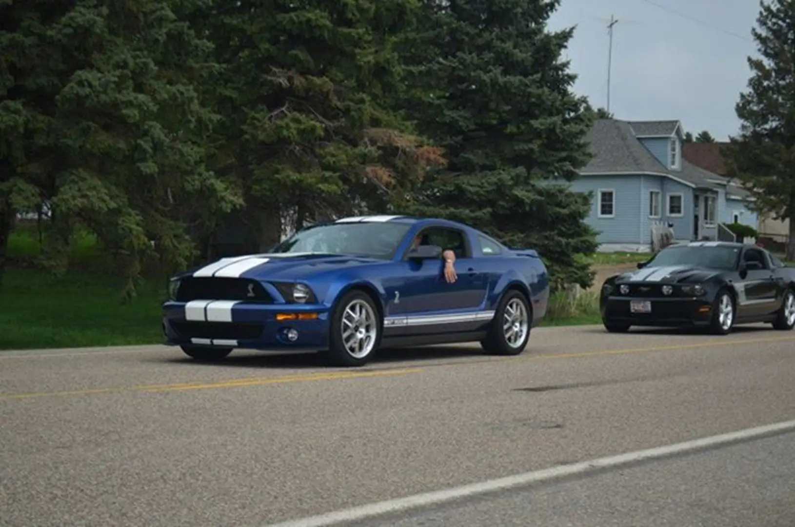 Blue sports car driving on rural road