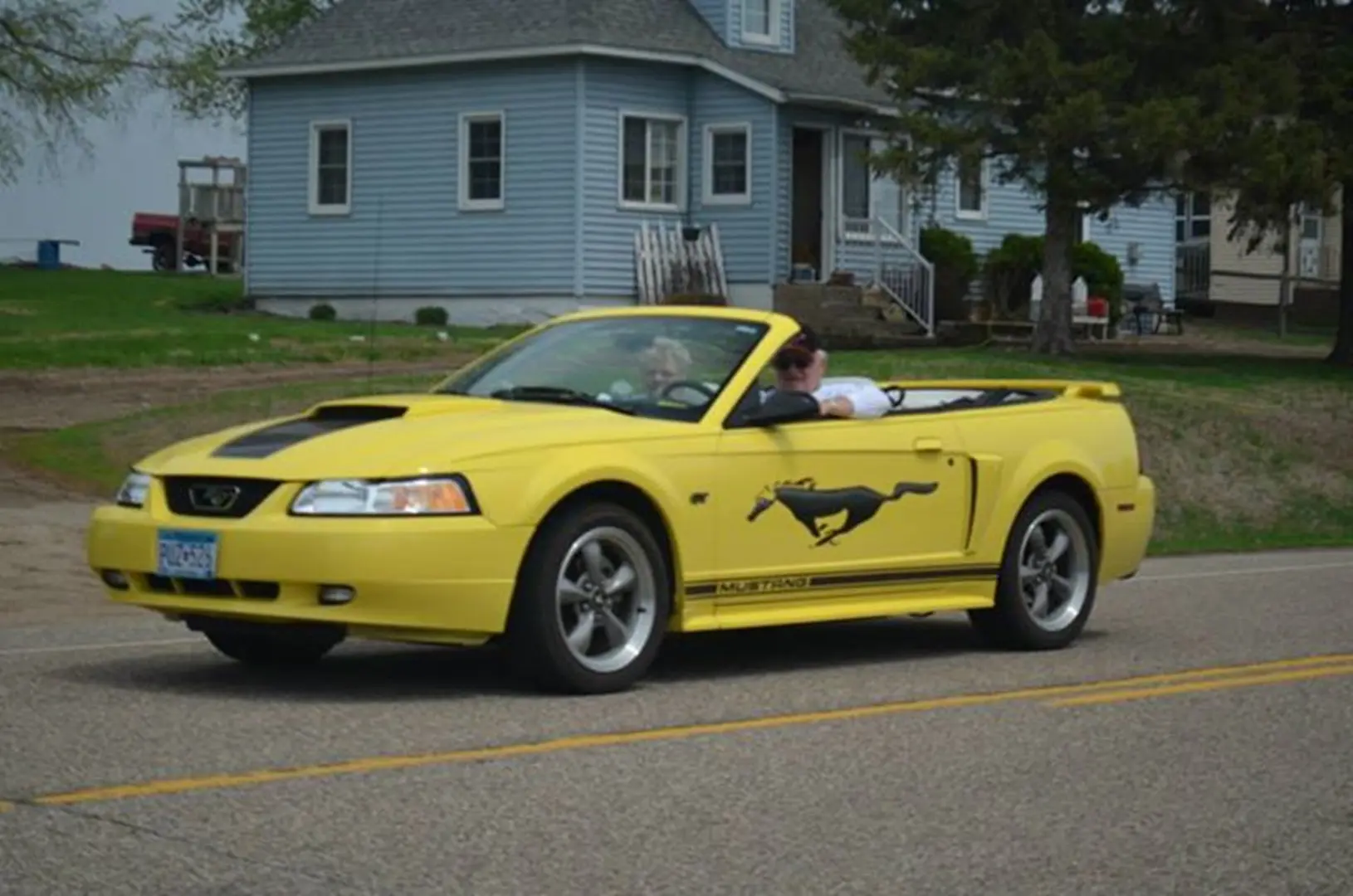 Yellow convertible driving on suburban road