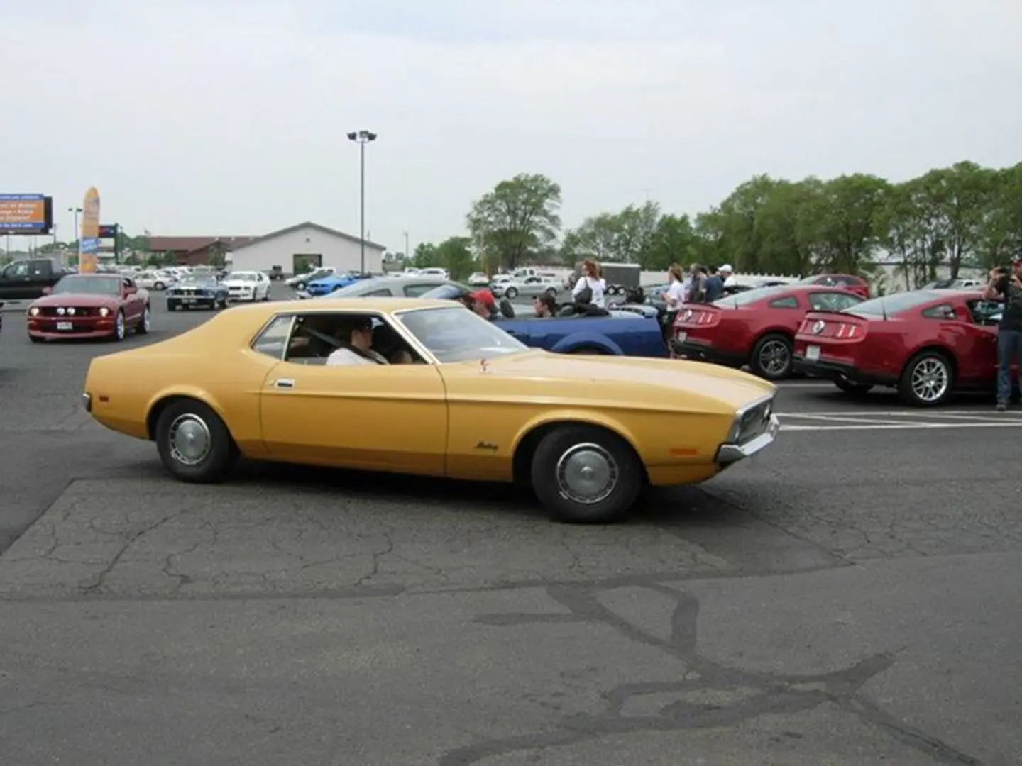 Vintage car driving in parking lot.