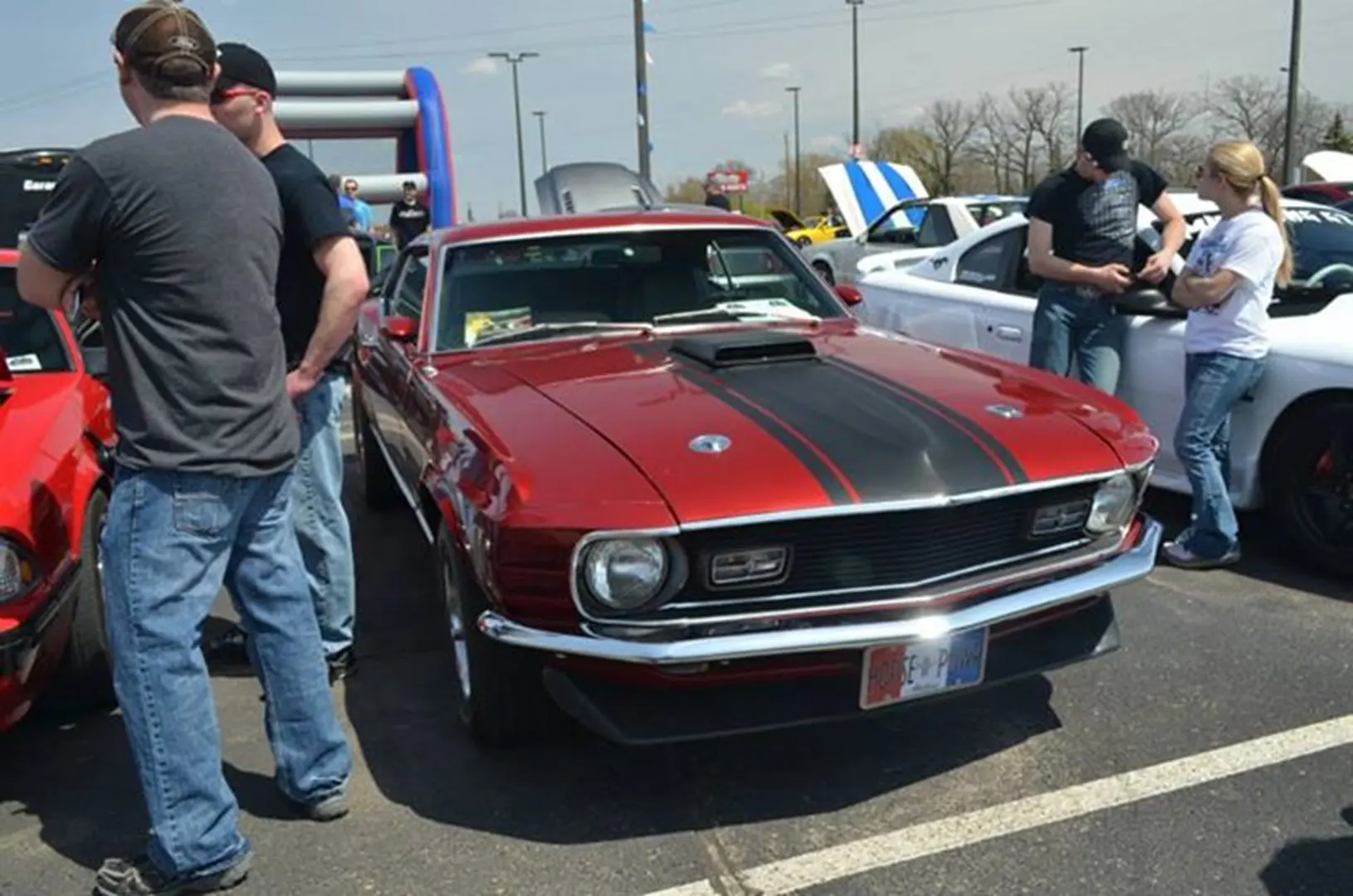 People admiring classic red vehicle