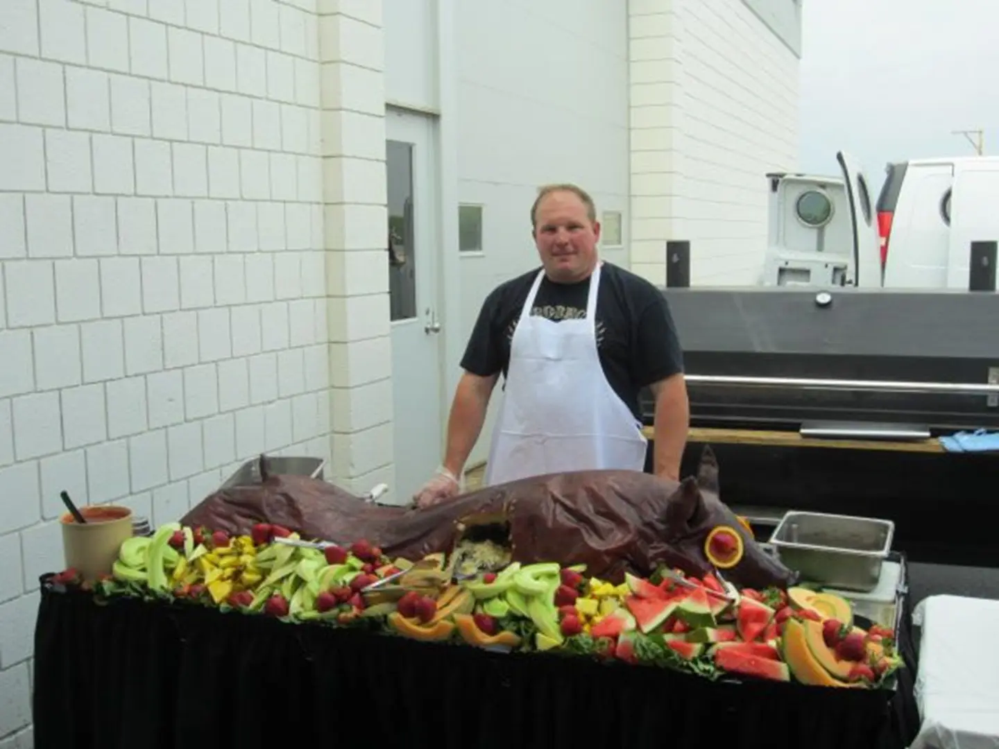 Chef with roasted pig and fruit display