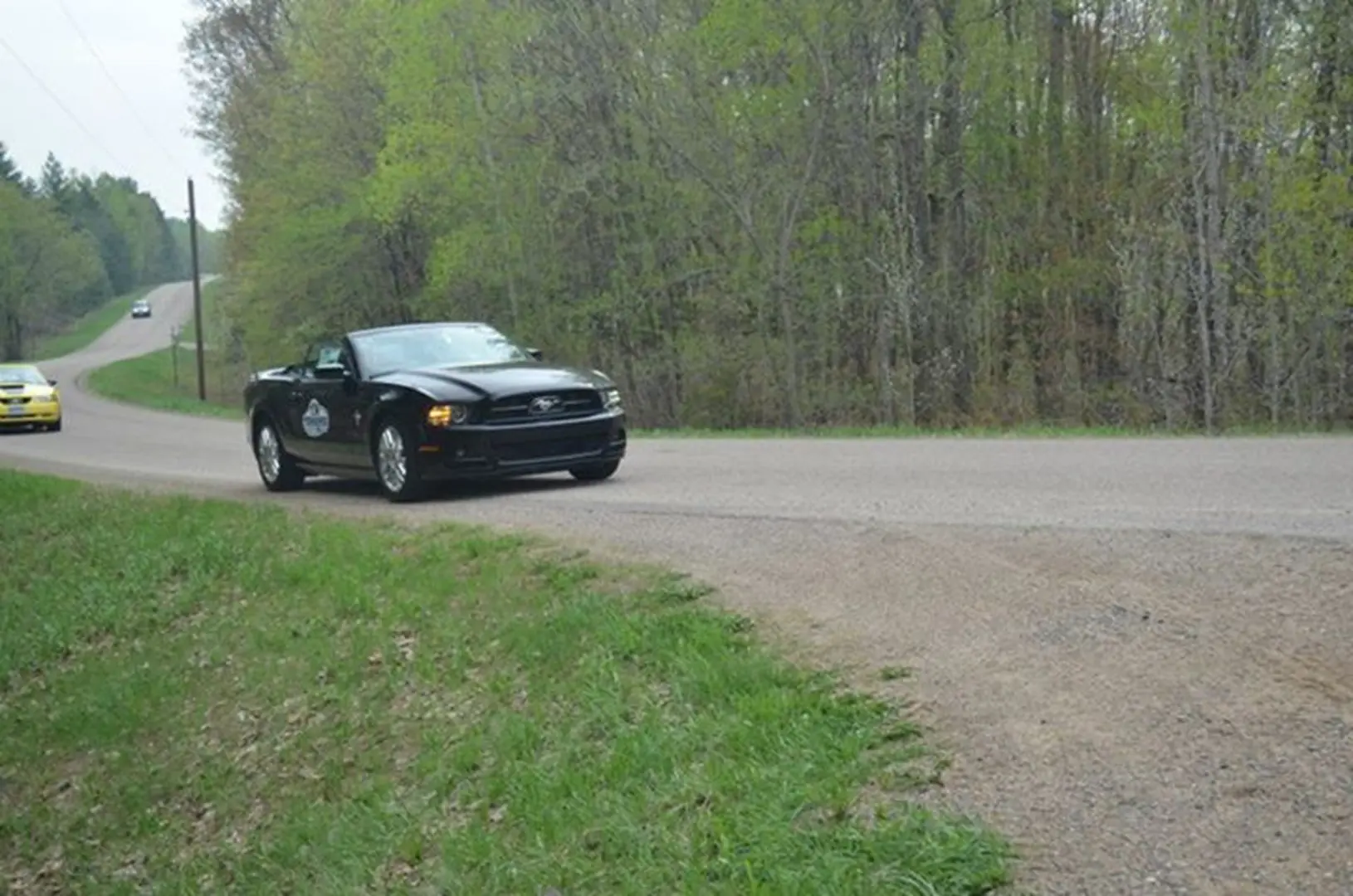 Black convertible driving on rural road