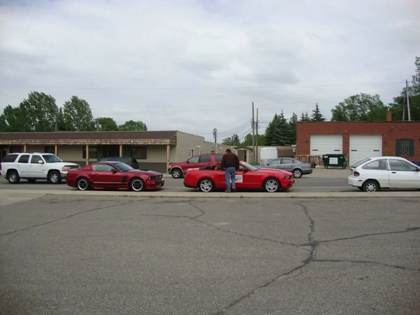 People standing by parked red cars