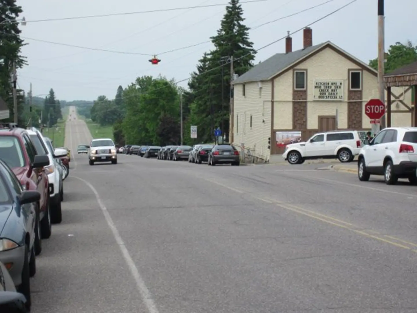 Street with parked cars and distant trees