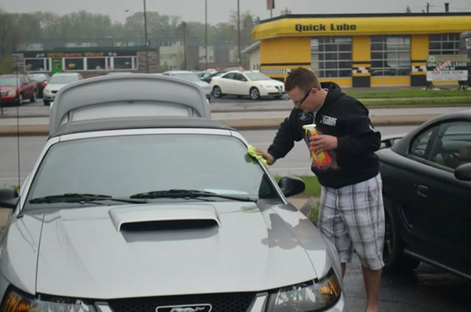Person wiping silver car with cloth