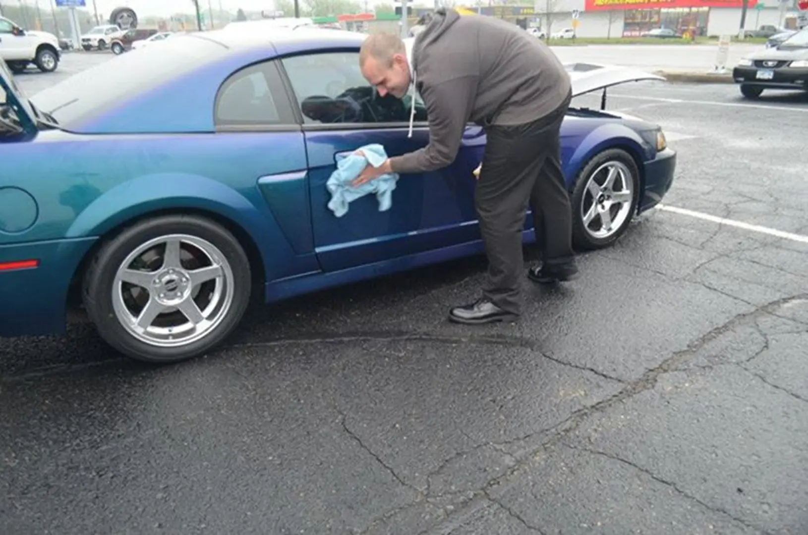 Man polishing blue car with cloth