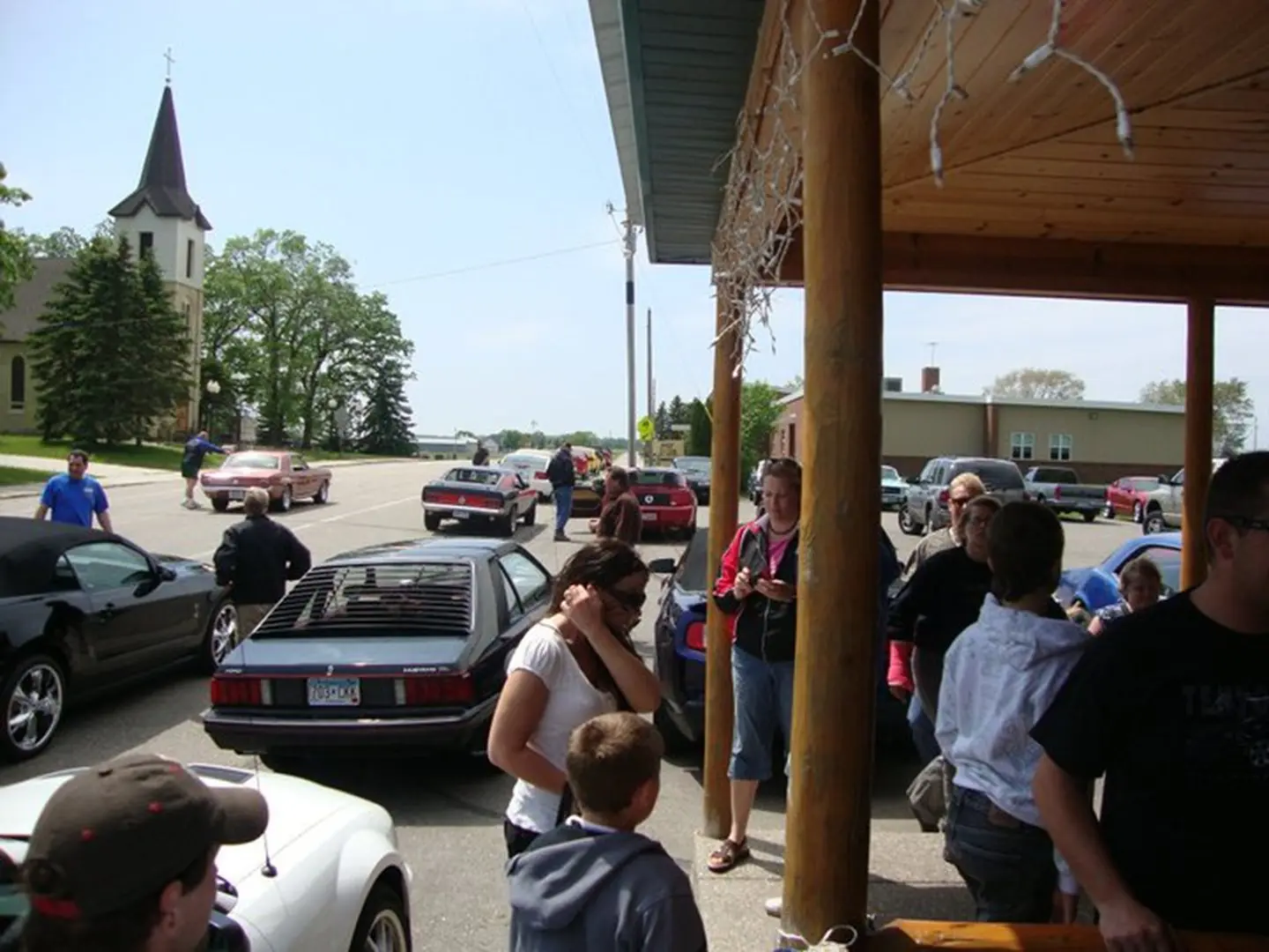 Small crowd outside, cars and building visible