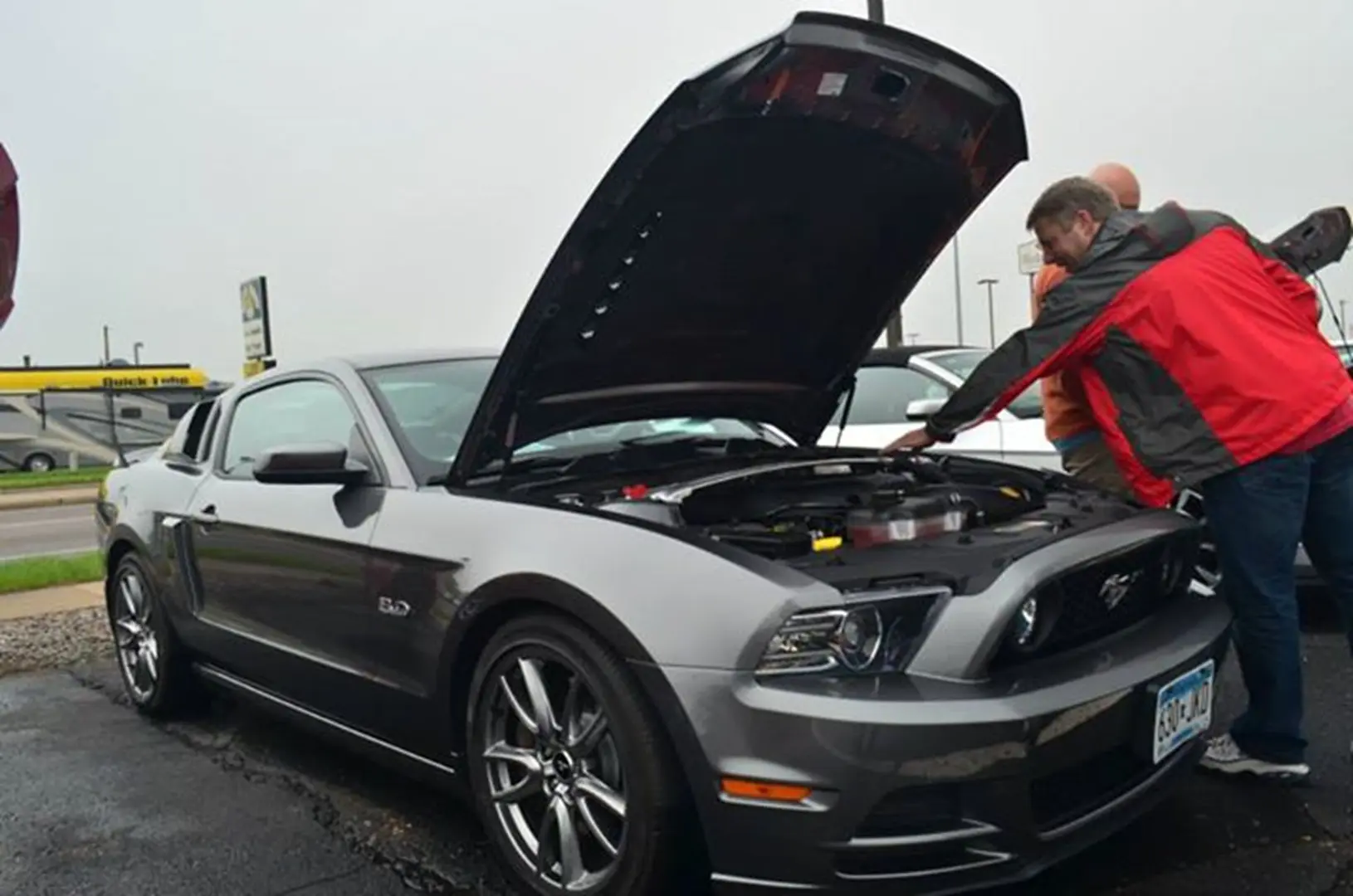 People inspecting a classic sports car