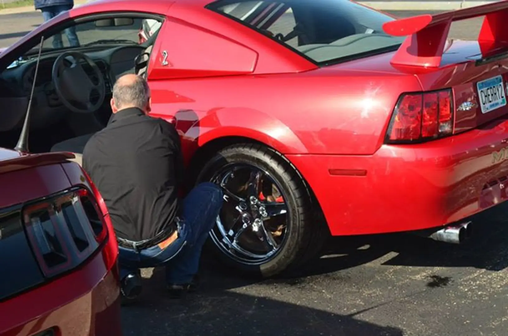 Man cleaning red sports car wheel