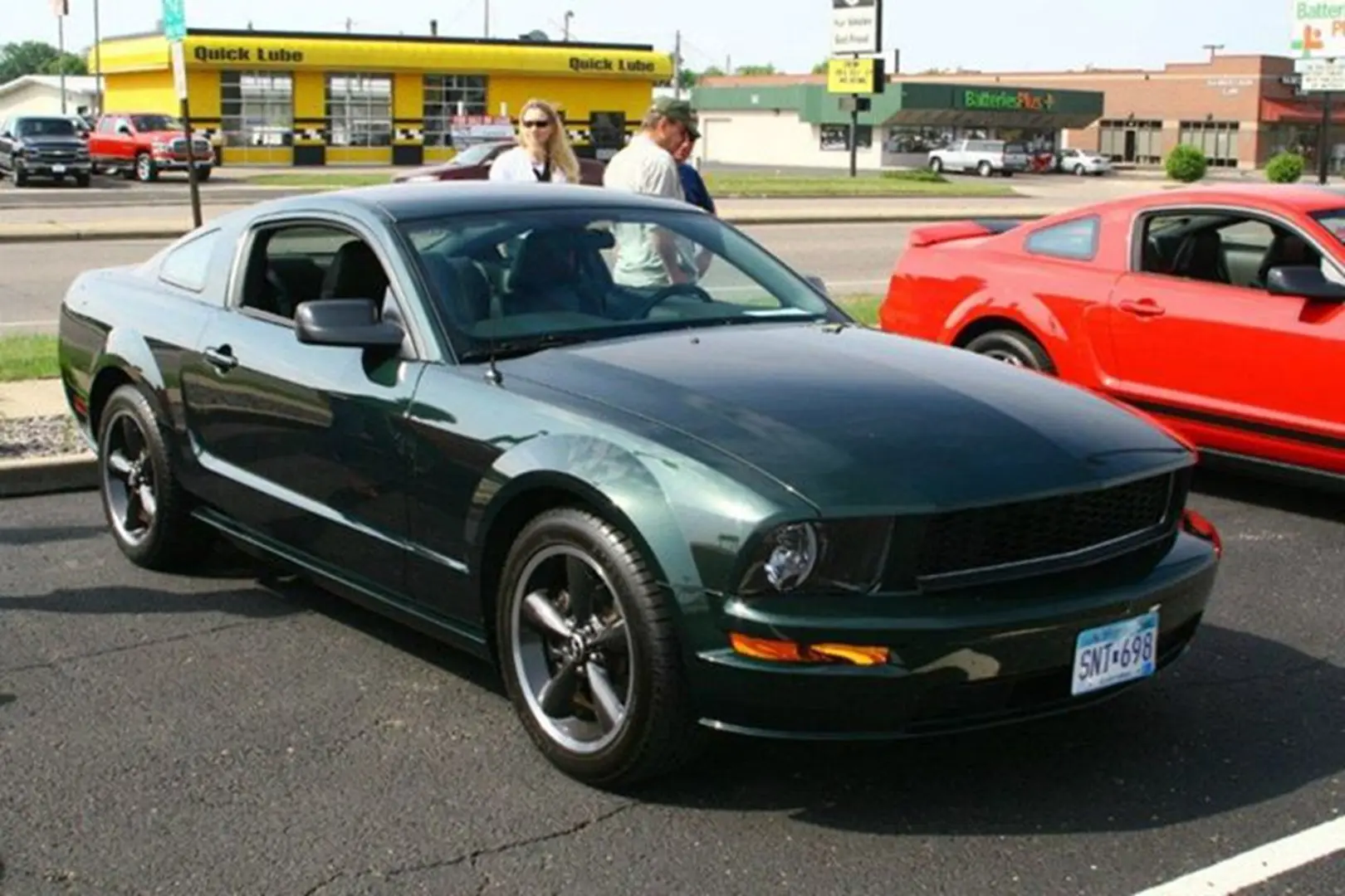 Dark green car and people nearby