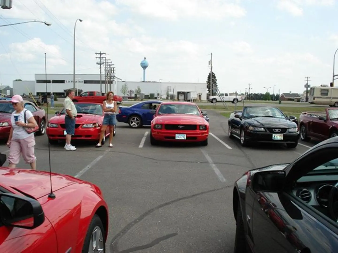 People gathered around colorful parked cars