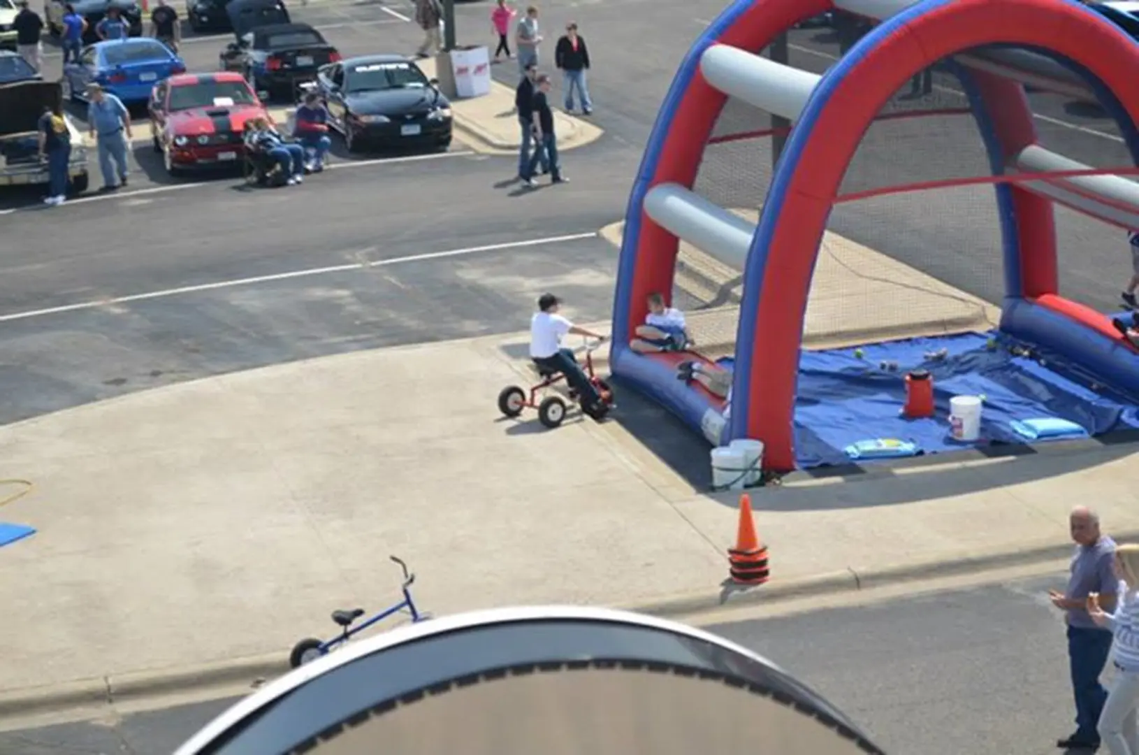 Child riding tricycle near inflatable play area