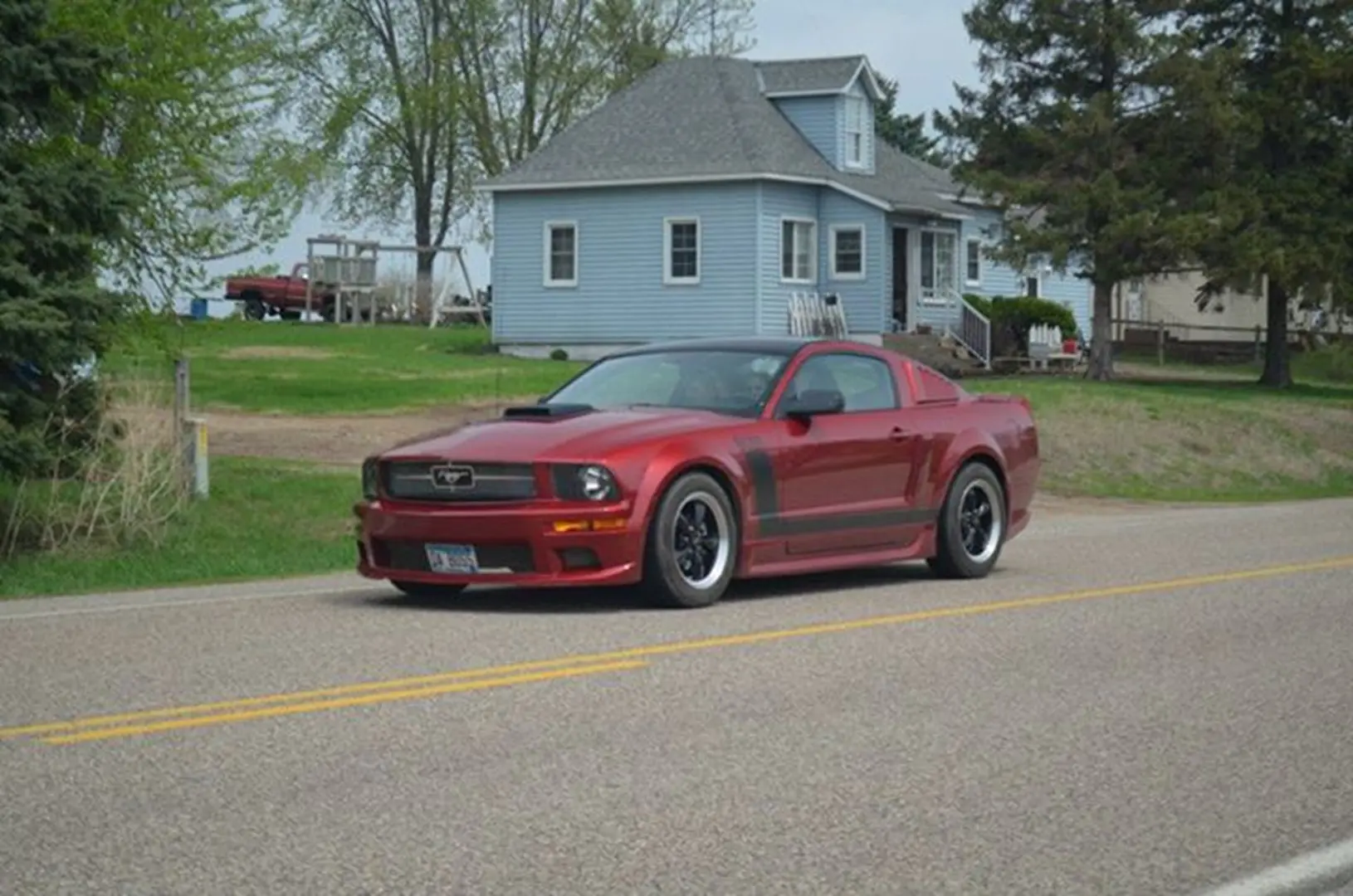 Red Mustang beside a blue house