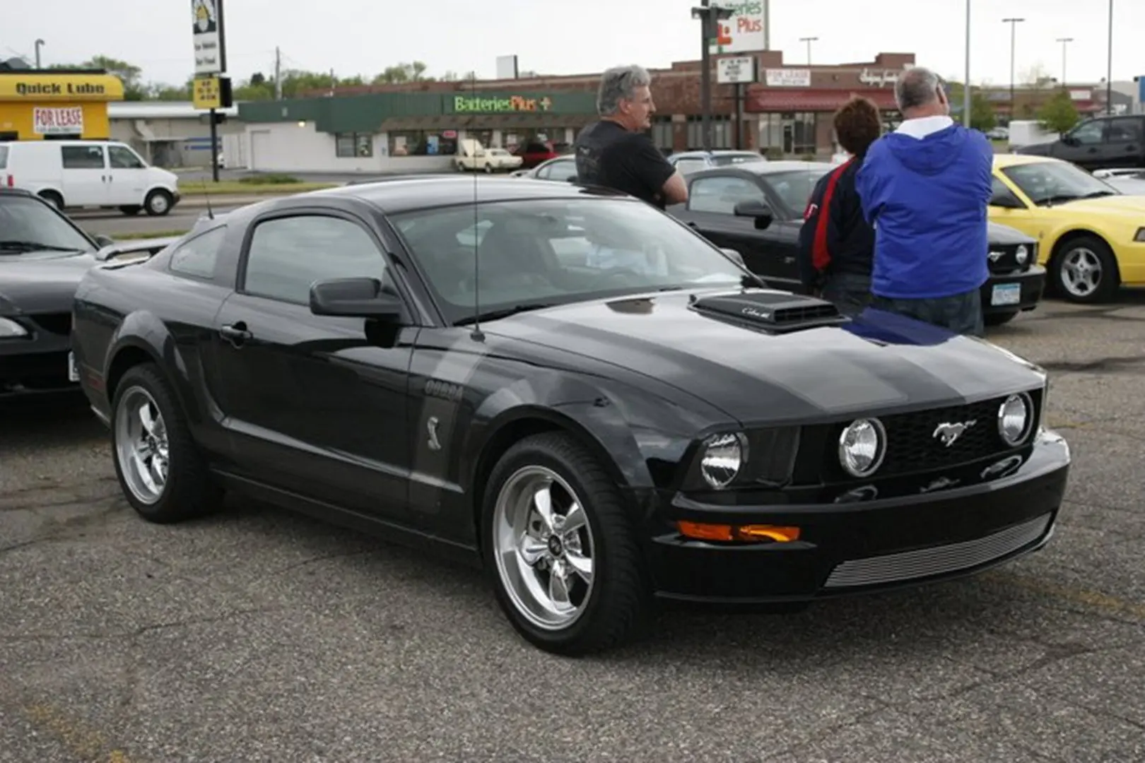 Group admiring black Mustang vehicle
