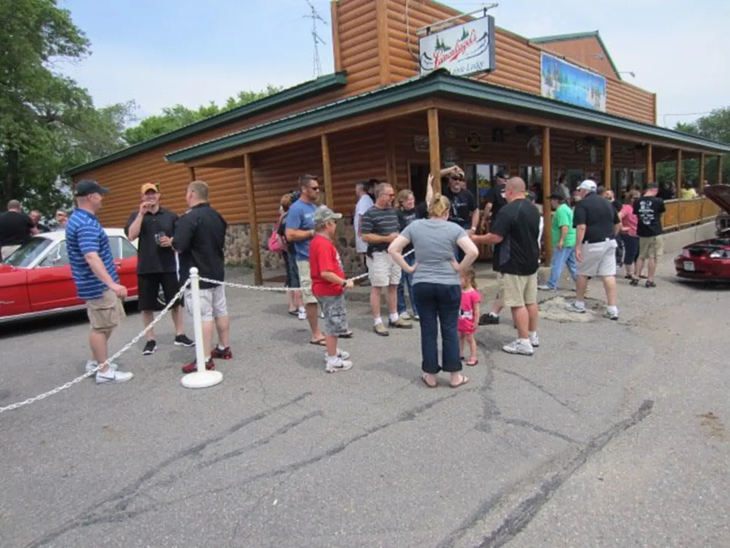 People gathering outside a log cabin building.