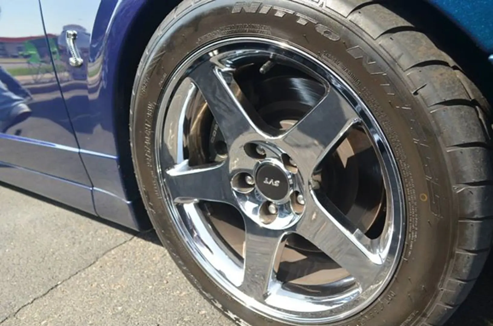 Shiny chrome car wheel on pavement