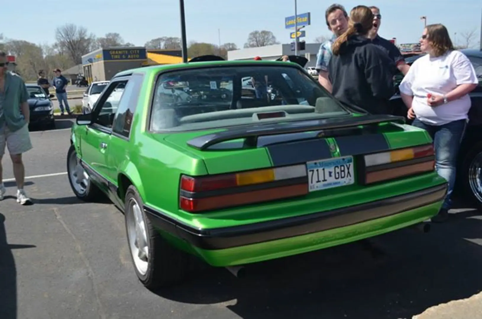 People admiring a green classic car