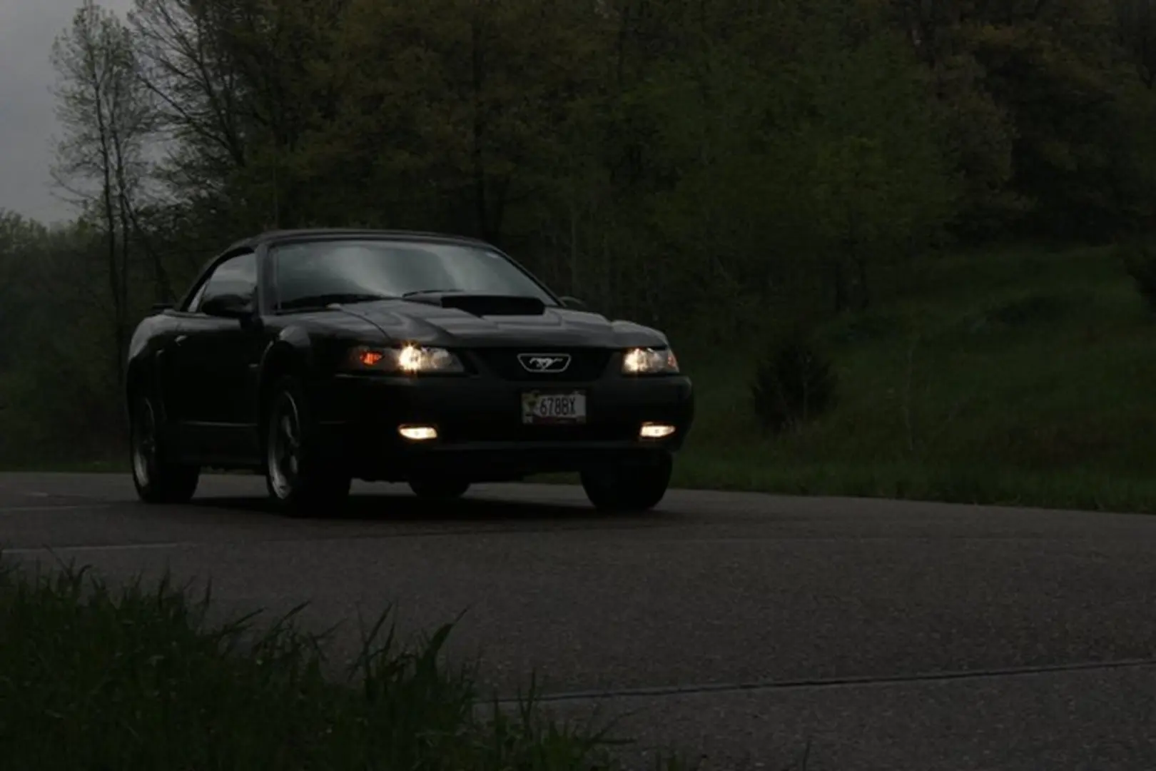 Dark car with headlights on road