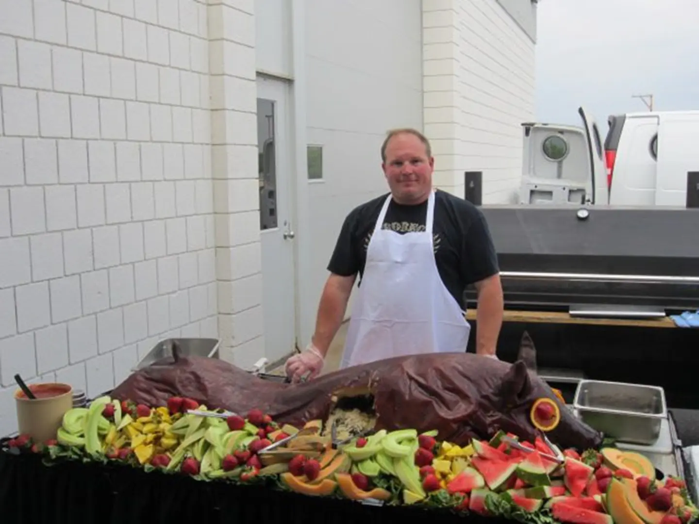 Outdoor pig roast with colorful fruit arrangement
