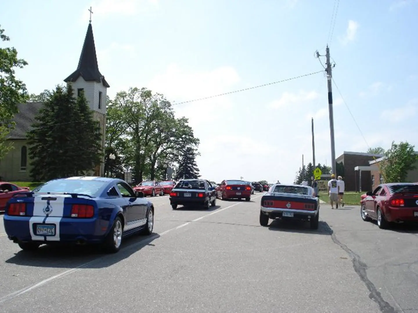 Classic car parade passing church