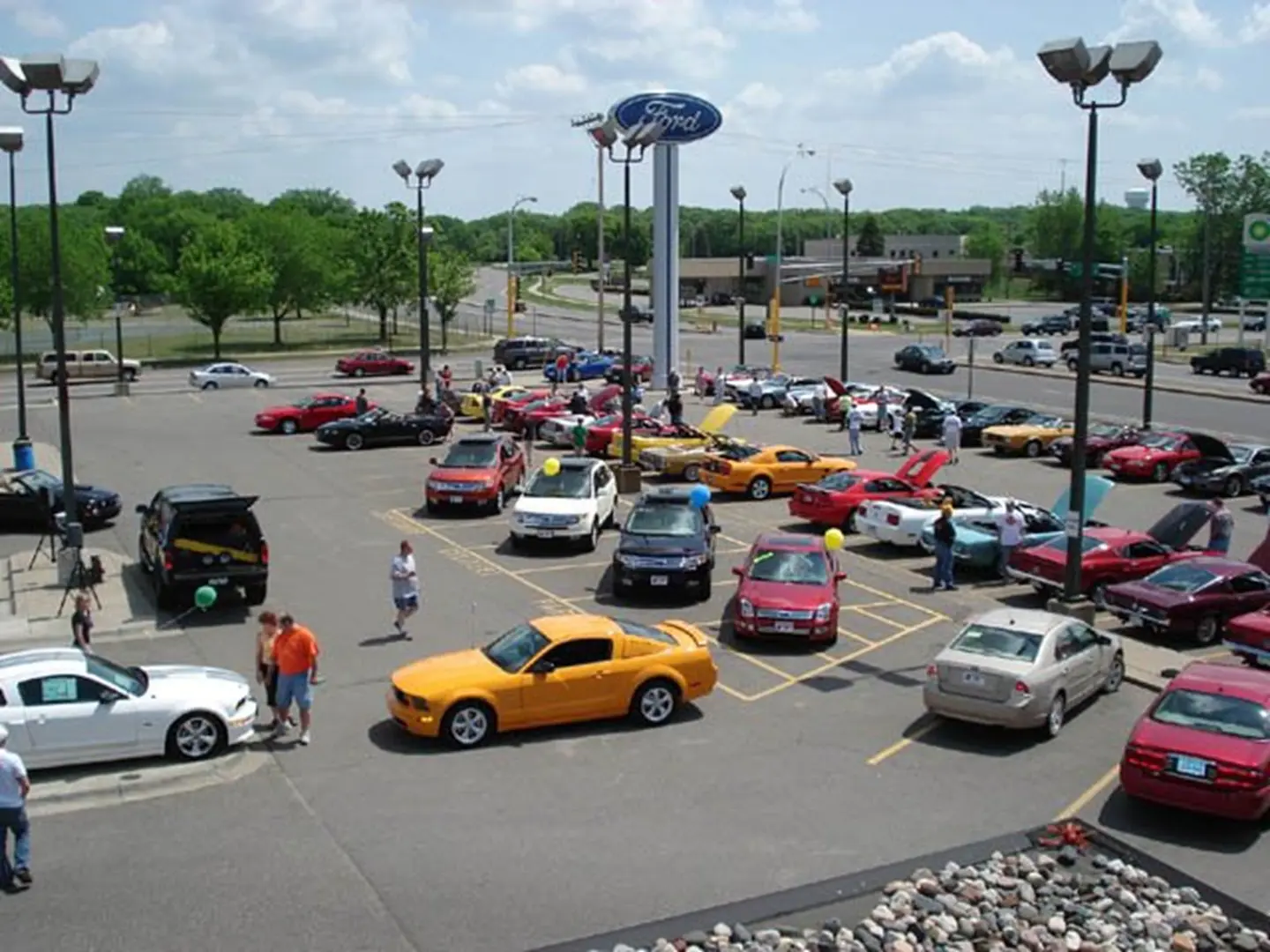 People gather around vibrant cars at dealership