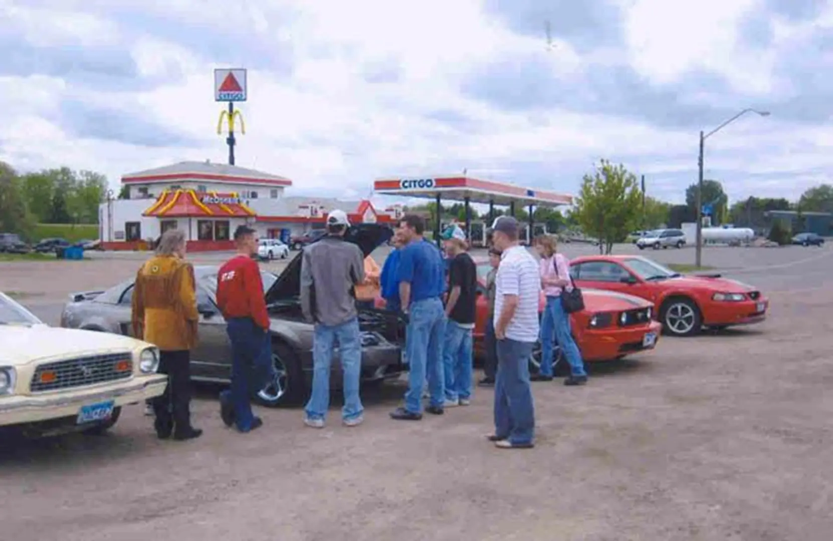 People inspecting cars in parking lot