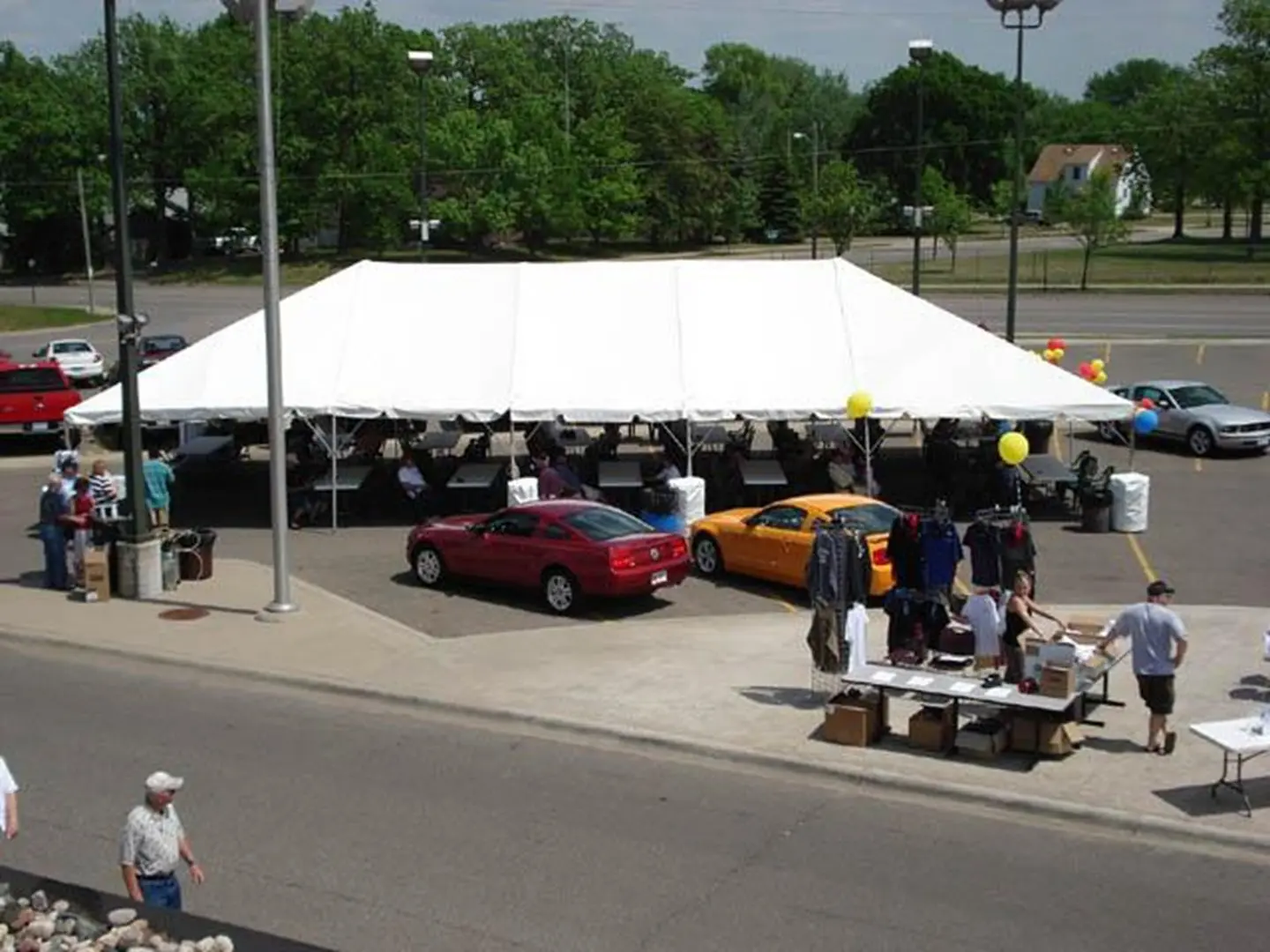 Community gathering with parked cars and tables