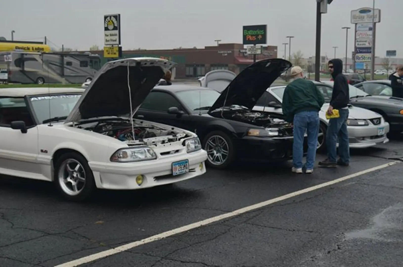People inspecting cars at parking lot