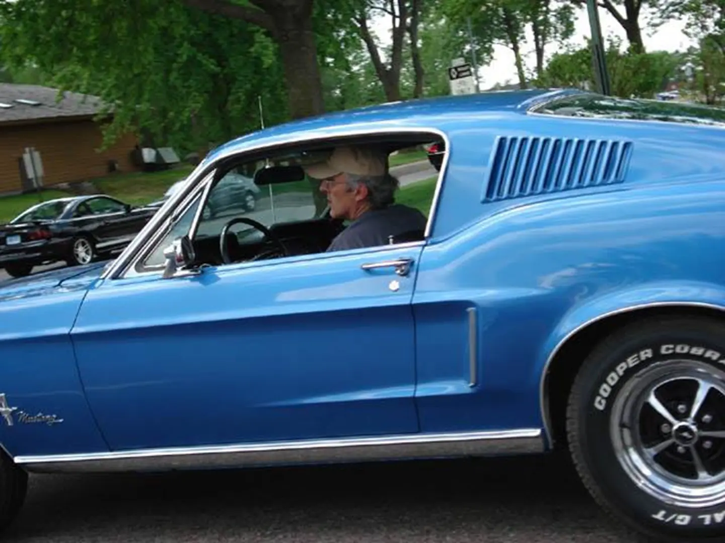 Blue vintage Mustang driving on street