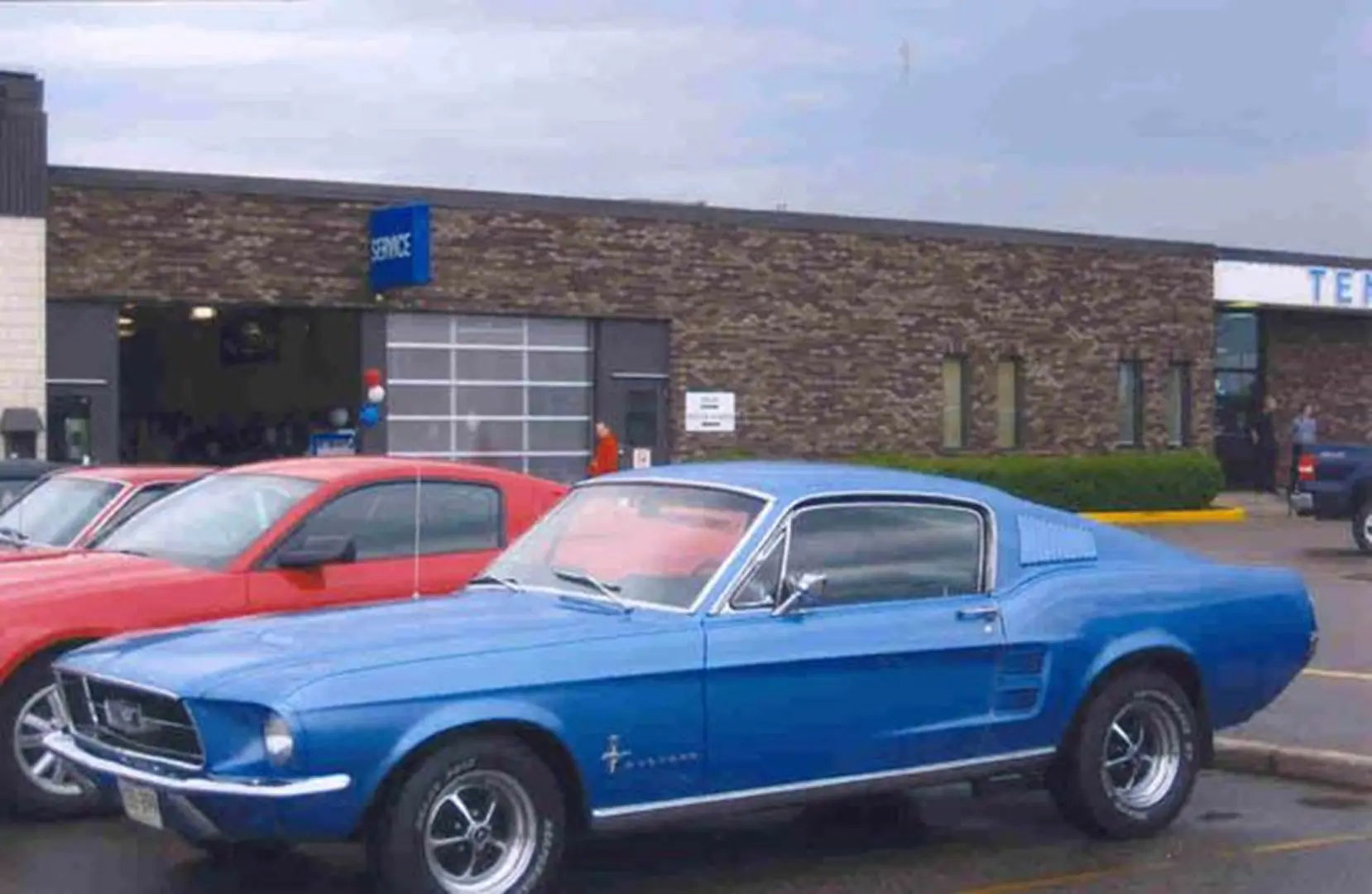Blue vintage Mustang parked outside garage