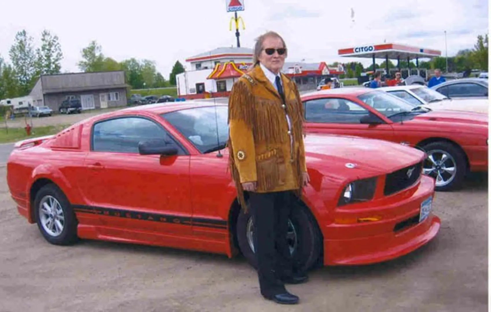 Person in fringed jacket beside car