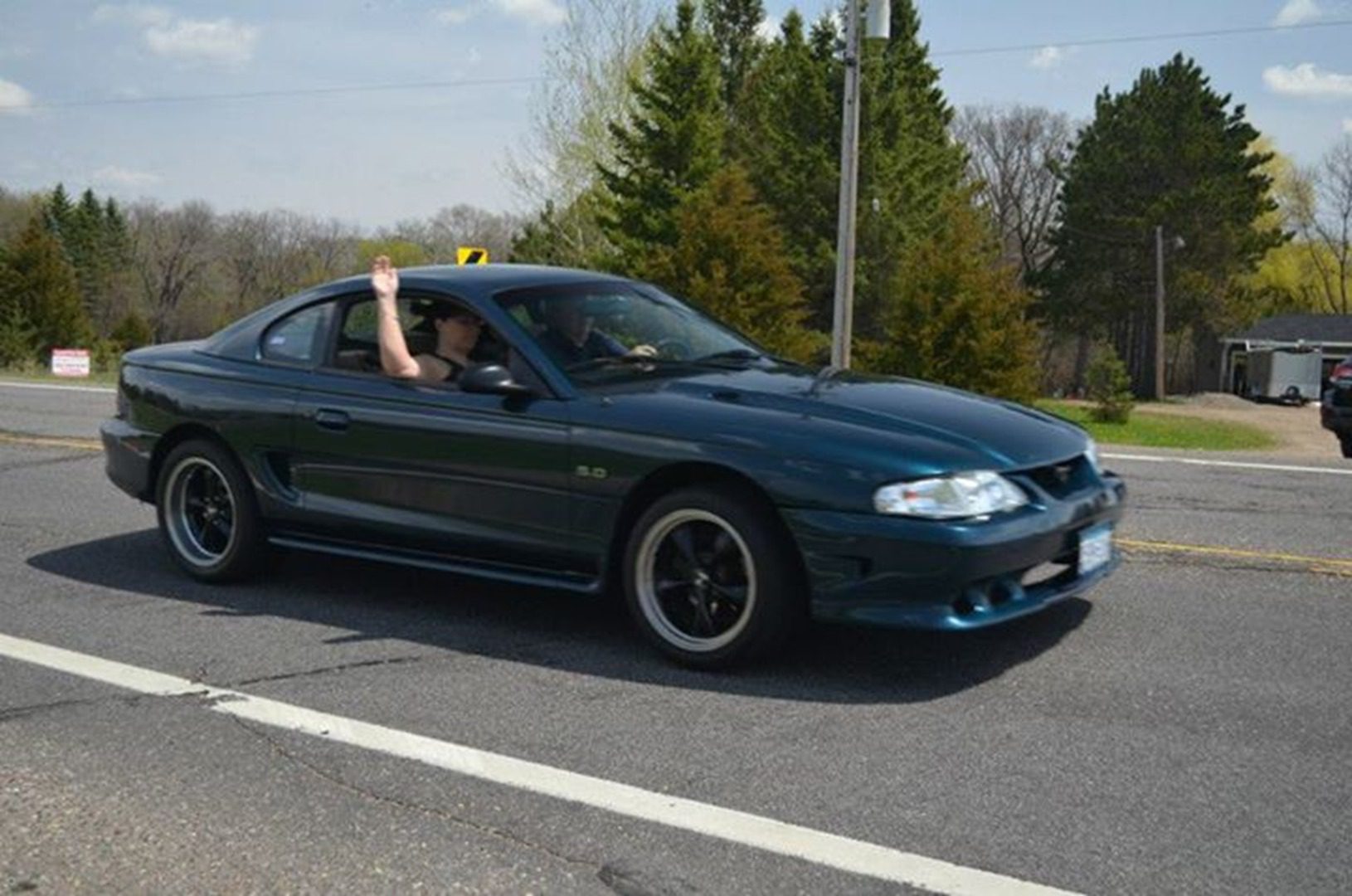 Person waving from moving car