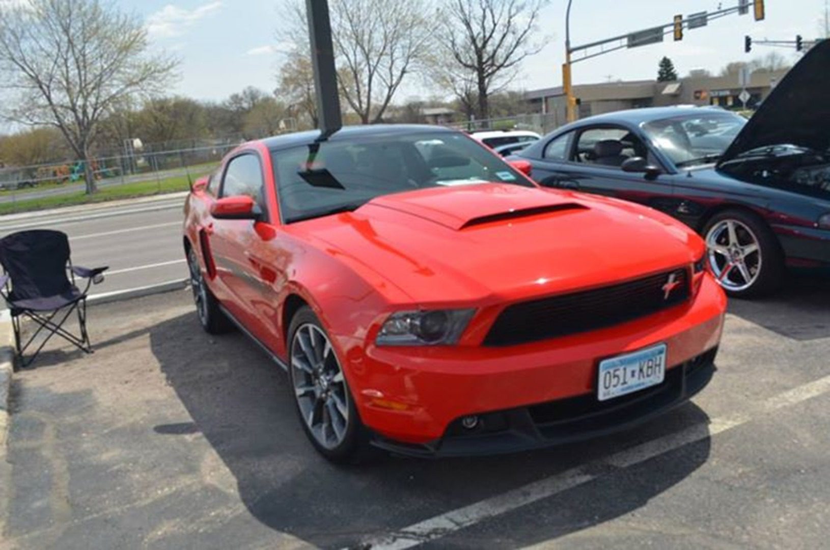 Shiny red car with open hood nearby.