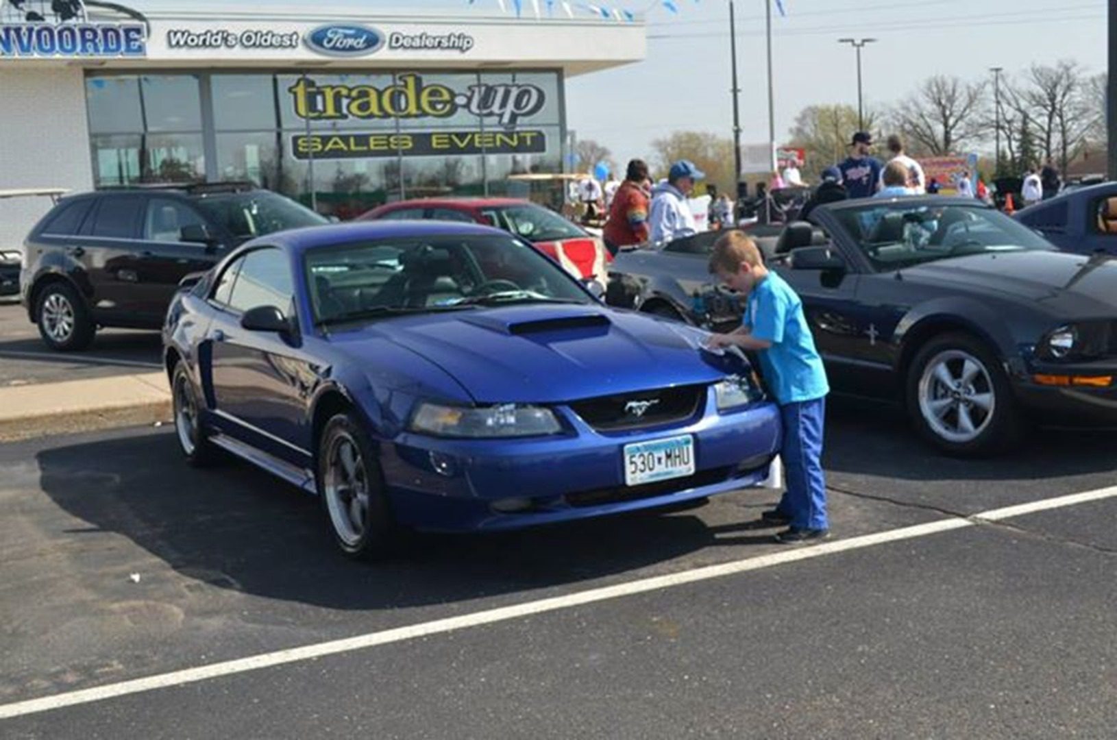 Young boy inspects sports car at dealership